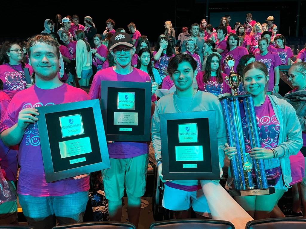 Four students holding plaques, trophies
