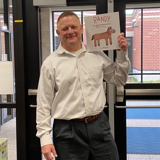 Adult holding book called "Randy" with a horse on the cover