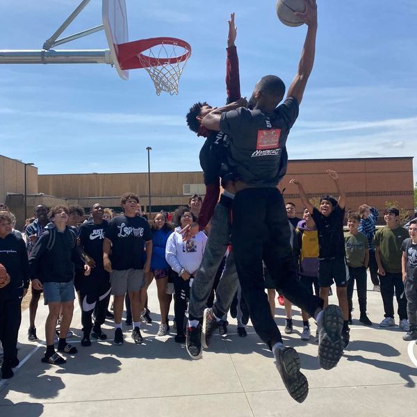 Basketball players play with students at recess