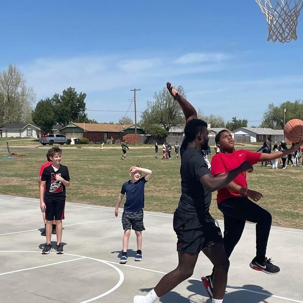 Basketball players play with students at recess